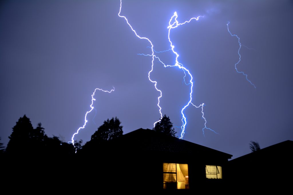 lightning storm above a house with lights on